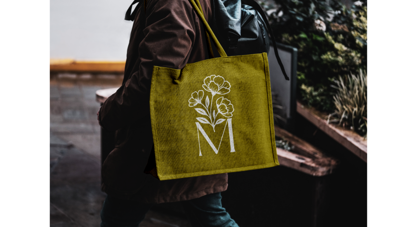 Sac en toile jaune avec des roses et un "M" blanc sur le devant.