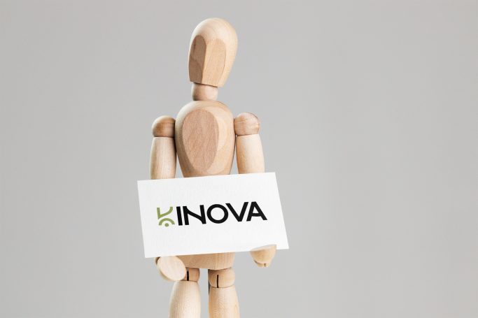 Mannequin en bois tenant une carte avec le logo "INOVA".