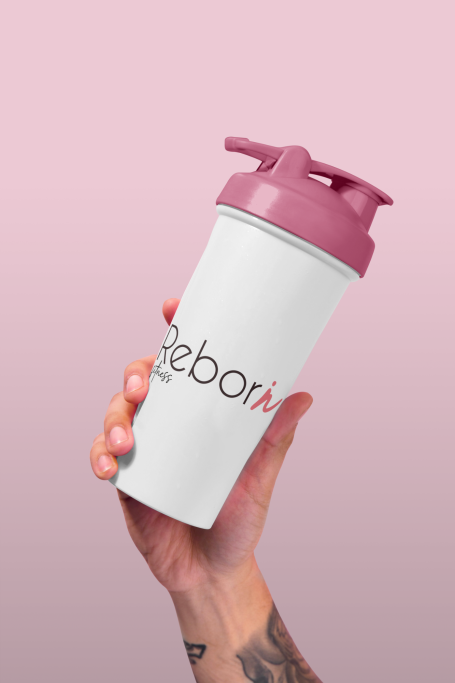 Gobelet de mélange avec un couvercle rose dans une main, sur fond rose dégradé.