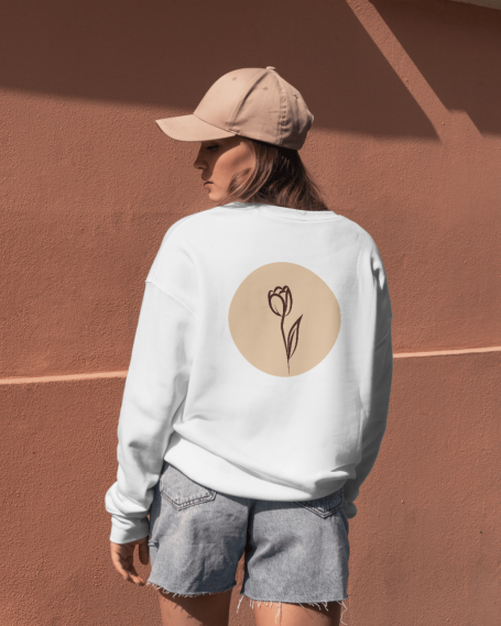Sweatshirt blanc avec un motif floral sur le dos, porté par une personne de dos.