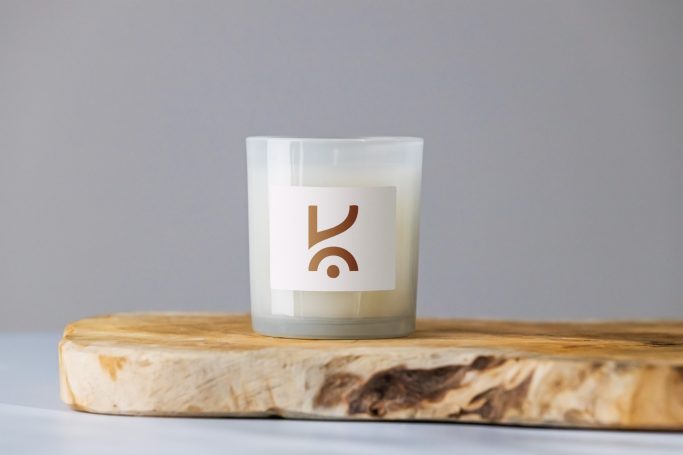 Bougie parfumée sur un support en bois clair.