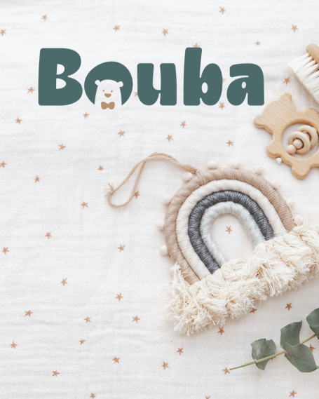 Texte "Bouba" avec un arc-en-ciel en tissu et des accessoires en bois sur fond clair.