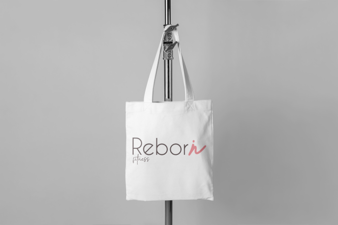 Sac en toile blanc suspendu, portant le logo "Reborn" en rouge et noir.