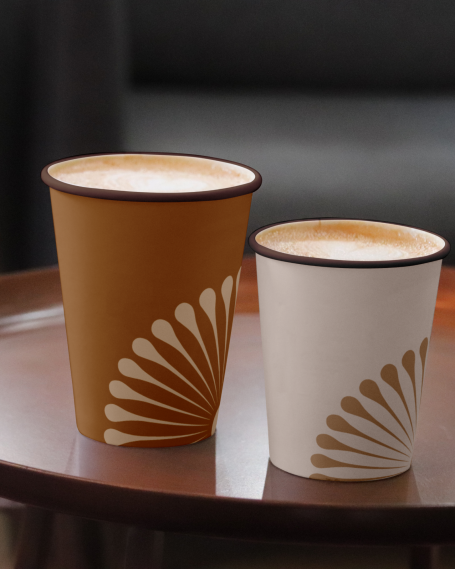 Deux tasses en papier, une marron et une blanche, avec un motif en éventail.