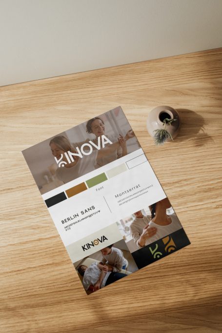 Brochure de l'entreprise Kinova sur une table en bois, avec un pot de plantes en arrière-plan.