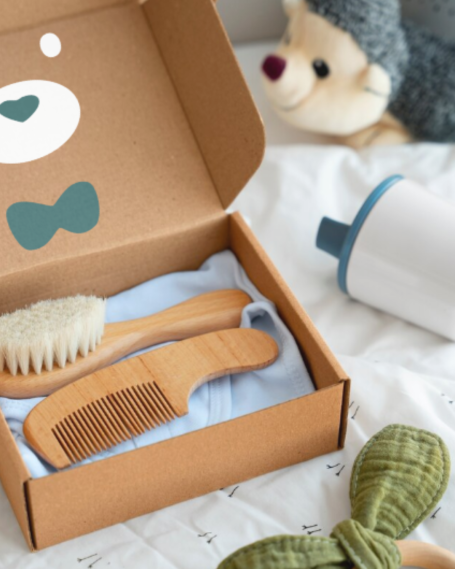 Coffret contenant une brosse et un peigne en bois, avec une peluche en arrière-plan.