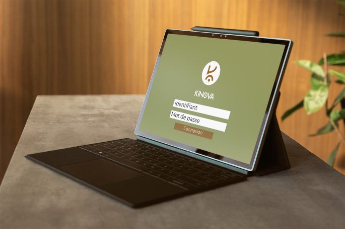 Ordinateur portable ouvert sur un écran de connexion avec un fond vert et une plante.